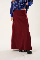 Falda larga color borgoña, confeccionada en tela suave con acabado tipo piel de durazno y cierre invisible lateral.