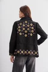 Campera estilo militar (army) color negro, con calce recto y ajuste interno en la cintura mediante cordón con borlas. Presenta bordados con apliques de lentejuelas en el cuello, bolsillos frontales y puños.