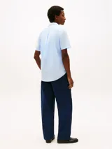 Camisa de manga corta Tommy Hilfiger en color celeste, confeccionada en tejido de popelina con tecnología flex. Presenta cuello clásico, cierre frontal con botones y el logo de la marca bordado en el pecho.