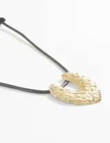 Collar con cordón negro ajustable y dije dorado con textura irregular.