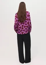 Camisa de tejido fluido color bordó con estampado geométrico abstracto en tonos morados y blancos, cuello camisero, manga larga y cierre frontal de botones.