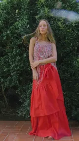 Pollera larga de lino color rojo, tipo envolvente o libro, con diseño de volados y gran movimiento.