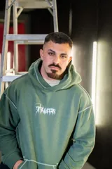 Canguro verde militar con capucha, estampado con texto en el frente y costuras a la vista.