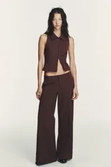 Chaleco de cuello solapa y manga sisa, color marrón con rayas verticales. Presenta cierre frontal con cremallera de doble cursor.