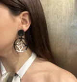 Aros colgantes con base circular negra y dije circular calado de asta blanca y negra.