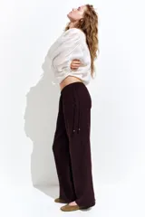 Pantalón marrón de corte holgado con piernas amplias y bolsillos al bies. Modelo de tiro bajo con elástico revestido y cordones para ajustar enlazados a los lados, decorados con cuentas en los extremos.