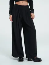 Pantalón de corte wide leg en color negro, con diseño de pinzas en la parte frontal, cierre y botón. Presenta una caída fluida y holgada.