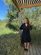 Vestido corto de lino color beige claro, con cuello mao, escote con botones de nácar, mangas tres cuartos con volados y ruedo con volado.