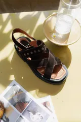 Sandalias de cuero marrón con textura de cocodrilo, diseño de tiras cruzadas con tachas metálicas plateadas y suela track negra de plataforma.