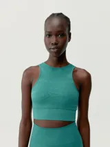 Top cropped de lycra color verde esmeralda, de sujeción media-alta, con tecnología 3D, tejido fit-tech, punto liso y canalé, calados decorativos, copas extraíbles y espalda atlética.