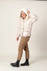 Campera puffer color crudo con brillo metalizado, con bolsillos delanteros, capucha con aplique de piel sintética desmontable y cierre frontal.