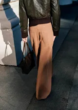 Pantalón jeans estilo wide leg de tiro medio color marrón claro, con diseño suelto, trabillas para cinto, cinco bolsillos y detalles de costuras en la cadera.