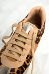 Zapatillas bajas de cuero con estampado animal print, detalles en cuero color marrón y puntera metalizada dorada.