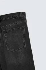 Bermuda de denim de algodón, color azul medio lavado, de corte ancho (baggy fit) y largo hasta la rodilla. Presenta cinco bolsillos y cierre frontal con cremallera y botón.