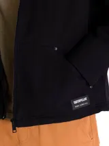 Chaqueta negra con cierre frontal, capucha forrada en sherpa gris y diseño de corte recto. Cuenta con bolsillos laterales y un bolsillo vertical en el pecho.