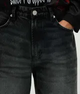 Pantalón de jean negro con efecto desgastado, de corte wide leg, con cintura con pasadores, cierre frontal con botón y cremallera, y bolsillos funcionales.