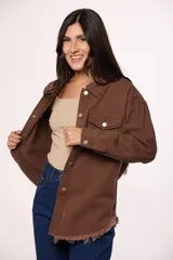 Sobrecamisa de jean color marrón, con cierre frontal de botones metálicos, bolsillos frontales con solapa y ruedo deshilachado.