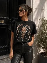 Remera de algodón color negro, de corte clásico y manga corta, con diseño gráfico estampado en el pecho que incluye un corazón místico rodeado de serpientes y estrellas.
