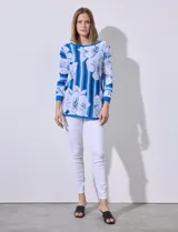 Buzo tejido en hilado fino, con cuello redondo y mangas 3/4. Presenta un estampado floral en tonos azules sobre un fondo a rayas verticales en diferentes tonos de azul.