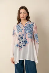 Túnica blanca de seda con bordados florales en azul y rojo, cuello mao con botones y mangas largas.
