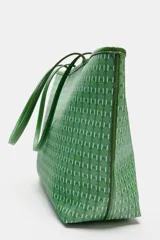 Bolso de hombro tipo shopper de color verde con cuerpo estampado geométrico, doble asa de hombro fina y detalles de pespuntes a contraste. Cuenta con compartimento interior con cremallera y cierre mediante botón imantado.