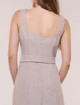 Vestido midi abotonado verde melange, con escote recto, tirantes anchos y falda de calce recto con vuelo sutil. Tiene abotonadura frontal completa con botones estilo carey, cinto textil con hebilla para ajustar la cintura y bolsillos laterales.