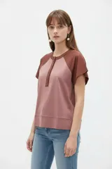 Remera de manga corta con diseño color block en tonos rosado y marrón, con escote en V y cartera con botones frontales.