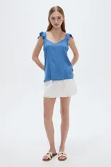 Musculosa amarilla de viscosa, con cuello en V y breteles anchos decorados con volados. Presenta un corte holgado.