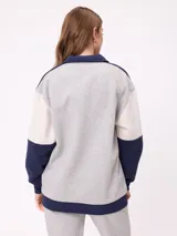 Sweater estilo rugby de Rusty, con diseño color block en tonos bordó, azul marino y verde. Presenta cuello polo en color crema con cierre frontal de botones, mangas largas con puños elásticos y logo de la marca bordado en el pecho.