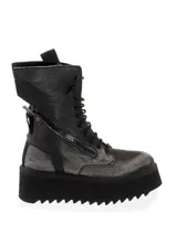 Bota de cuero negra con cordones y cierre lateral con cremallera. Tiene plataforma con suela dentada y tirador trasero.
