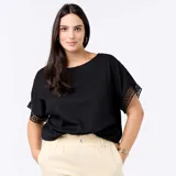 Remera negra de corte holgado y escote redondo, de manga corta con detalles de bordado y encaje macramé en las mangas.