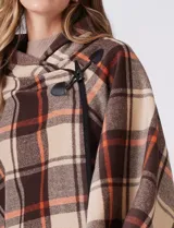 Capa de tejido cuadrille con diseño de cuadros en tonos marrón, beige y naranja. Presenta un cierre frontal con botón tipo trenca y bordes con ribete negro.