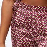 Conjunto de pijama largo de dos piezas con camisa de manga corta con botones y pantalón largo con estampado geométrico en tonos púrpura, rosa y blanco.