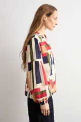 Camisa de manga larga con estampado geométrico multicolor en tonos beige, rojo, azul marino y verde, cuello mao y cierre frontal con botones.