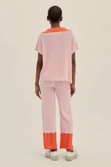 Pantalón tejido color rosa con terminaciones en crochet color naranja, de largo hasta los tobillos, con un fit holgado y cintura elastizada.