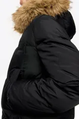 Campera tipo plumífero de largo medio y corte recto en tejido técnico, con cierre frontal, capucha con borde de pelo sintético desmontable y puños elásticos interiores. Presenta bolsillos laterales de vivo y etiqueta con logo en el pecho.