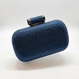 Cartera tipo clutch de mano en color azul, completamente cubierta de cristales brillantes y estructurada sobre herrajes metálicos plateados con cierre superior de broche y cadena metálica extraíble.
