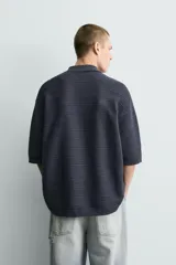 Polo de punto de algodón con textura acanalada, color verde militar, efecto lavado, cuello solapa, cierre frontal con botones y mangas cortas holgadas.