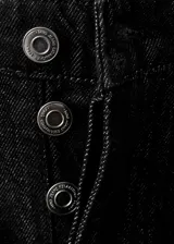 Jeans negros de tiro medio, estilo barrel y diseño balloon, confeccionados en algodón. Cuentan con cinco bolsillos, parches decorativos y cierre de botones.