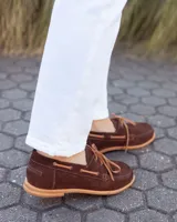 Zapato náutico de cuero gamuzado color marrón chocolate, con cordones y suela plana.