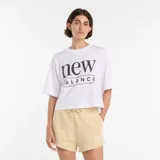 Remera blanca de corte holgado con cuello redondo y mangas cortas. Presenta un estampado gráfico con el logo de la marca en el centro del pecho.