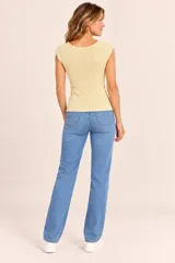 Remera de manga corta color manteca, confeccionada en tejido de punto acanalado, con escote redondo y detalles de apliques de cuentas o perlas pequeñas en el borde del cuello y las mangas.