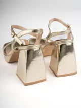 Sandalias plateadas con plataforma y tacón cuadrado, tira ancha sobre los dedos y pulsera con hebilla al tobillo.