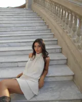 Vestido corto color beige, con cuello halter y espalda descubierta.