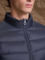 Campera puffer de plumas en color azul marino, con cierre frontal, cuello alto y diseño acolchado horizontal.