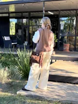 Chaleco tejido de punto en color chocolate, con cuello redondo y diseño sin mangas. Presenta un aplique frontal decorativo compuesto por tres figuras en forma de rombo en tonos tierra, bordeadas con hilo crudo.