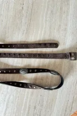 Cinturón doble de gamuza color chocolate, con apliques metálicos circulares y tachas decorativas.