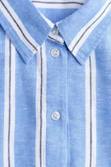 Camisa oversize confeccionada en mezcla de lino y viscosa, con diseño a rayas verticales en tonos celeste y blanco. Cuenta con cuello clásico, cierre frontal de botones, hombros caídos y mangas largas con puños abotonados.