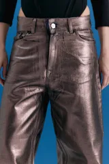Pantalón de jean estilo oversize de tiro medio-bajo, confeccionado en denim 100% algodón. Presenta un acabado metalizado en tono peltre con efecto lavado violeta, logrando un brillo irregular y profundo. Incluye avíos metálicos personalizados y badana de PU en la parte posterior.