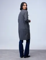 Cárdigan largo gris en tejido acanalado, con bolsillos delanteros, mangas largas y puños con aplique de botones.